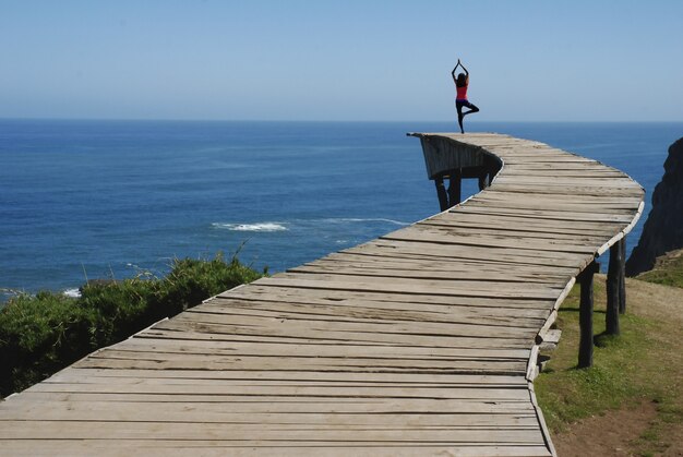 Frau macht Yoga auf dem Dock mit dem schönen Meerblick
