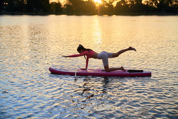 Frau macht Yoga-Übungen auf buntem Sup-Board