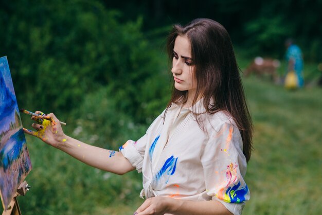 Frau malt ein Bild mit einem Wald Hintergrund