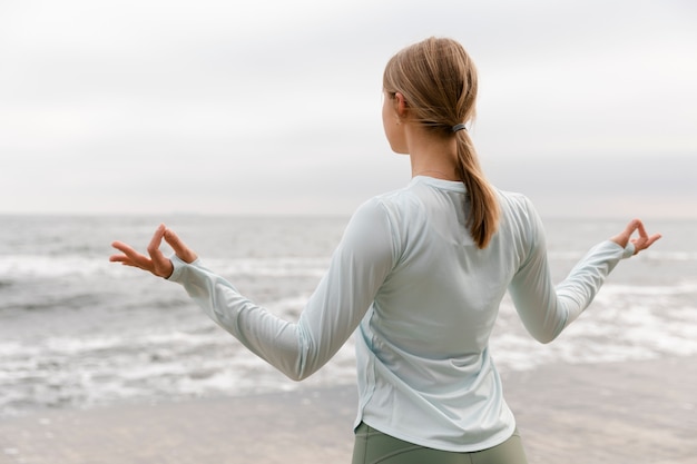 Frau meditiert am Meer mittlerer Schuss