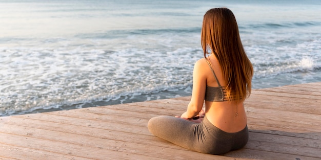 Frau meditiert neben dem Meer
