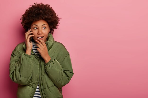 Frau mit Afro-Haarschnitt, trägt gestreiften Pullover und Winterjacke