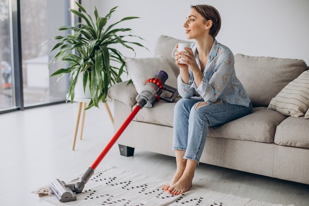 Frau mit Akkustaubsauger trinkt Kaffee