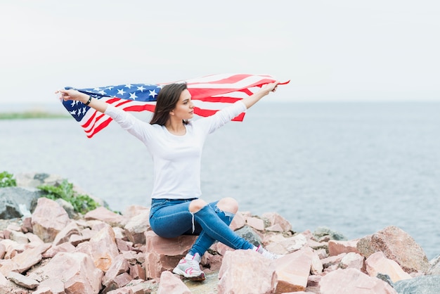 Frau mit amerikanischer Flagge nahe bei Meer