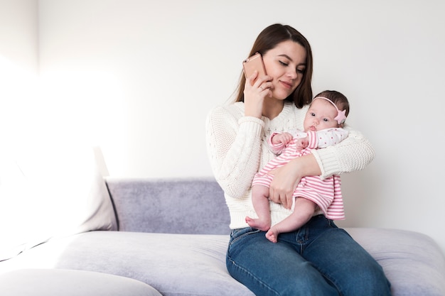 Frau mit Baby am Telefon sprechen