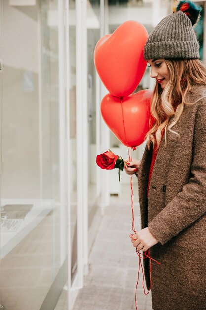 Frau mit Ballonen und stieg nahe Schaufenster