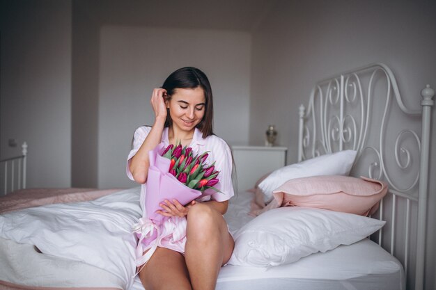 Frau mit Blumenstrauß von Blumen im Schlafzimmer