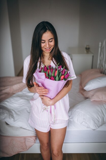 Frau mit Blumenstrauß von Blumen im Schlafzimmer