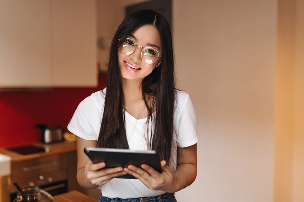 Frau mit braunen Augen mit Lächeln, das eine Tablette hält