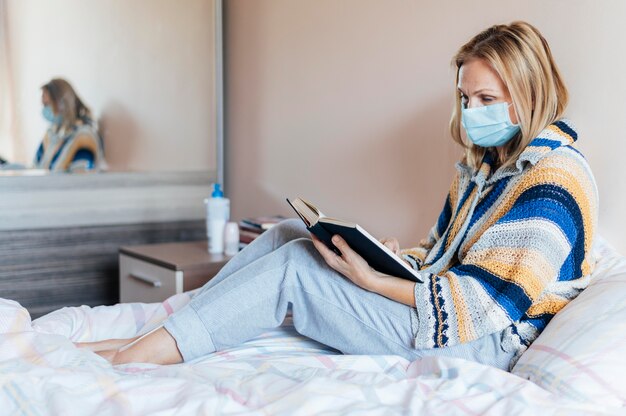 Frau mit Buch und medizinischer Maske in Quarantäne