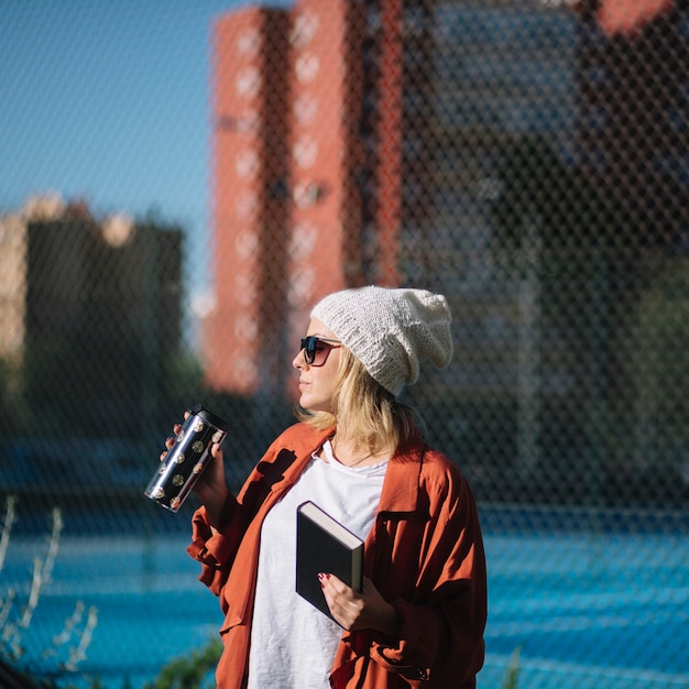 Frau mit Buch und Thermosflasche auf Straße