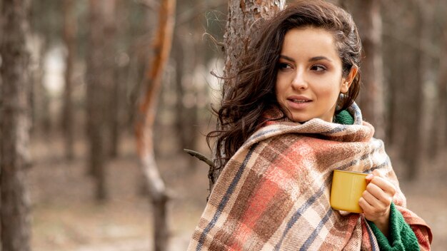 Frau mit Decke und Teetasse in der Natur