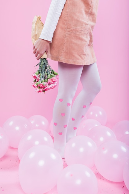 Frau mit dem Blumenblumenstrauß, der auf Boden mit Ballonen steht