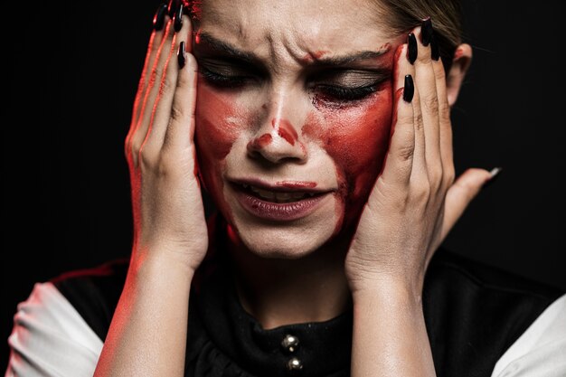 Frau mit dem blutigen Make-up, das ihren Kopf hält