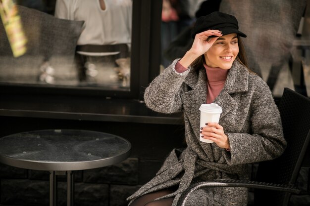 Frau mit dem Kaffee, der außerhalb des Cafés sitzt