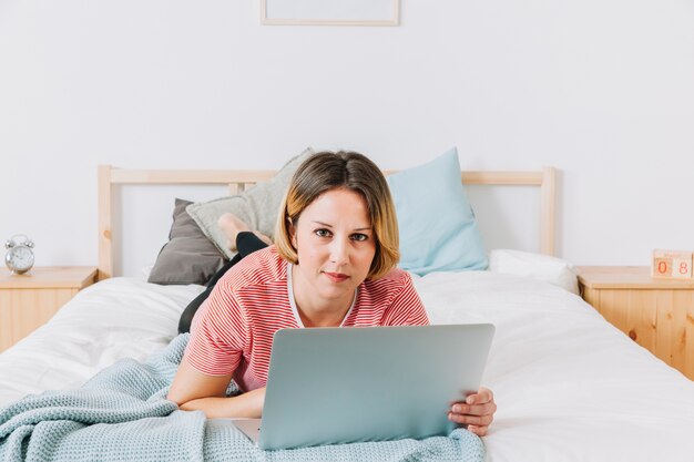 Frau mit dem Laptop, der Kamera betrachtet