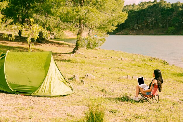 Frau mit dem Laptop, der nahe Zelt sitzt