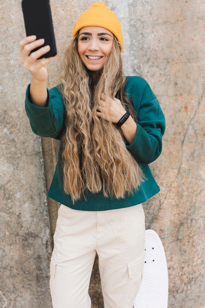 Frau mit dem Skateboard, das selfies nimmt