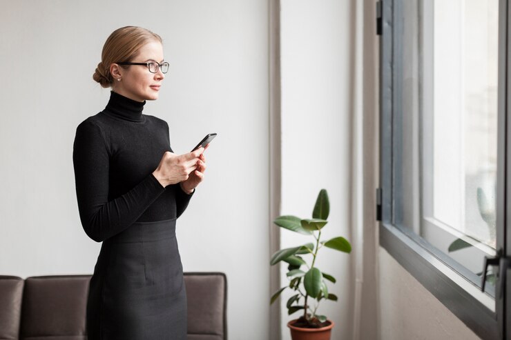 Kostenlose Foto frau mit dem telefon, das auf fenster schaut