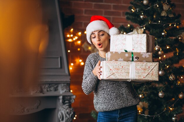 Frau mit den Geschenken, die vor Weihnachtsbaum stehen
