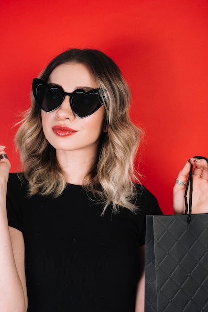 Frau mit den Gläsern, die schwarze Freitag-Einkaufstasche halten