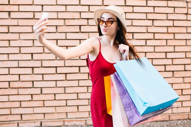 Frau mit den Papiertüten, die für selfie aufwerfen