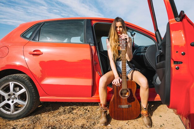 Frau mit der Gitarre, die im Auto balanciert