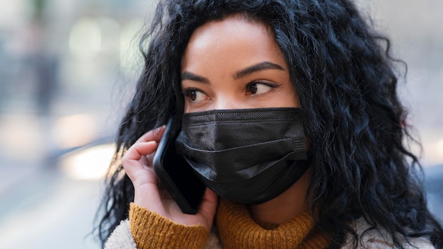 Frau mit der medizinischen Maske, die am Telefon spricht