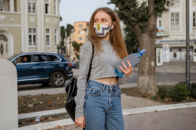 Frau mit der medizinischen Maske, die eine Flasche Wasser hält