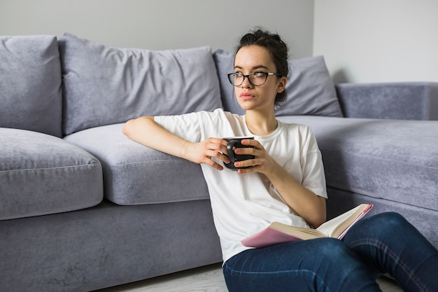 Kostenloses Foto frau mit der schale und buch, die weg schauen