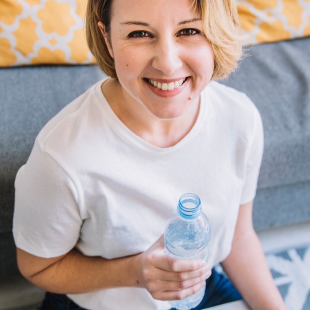 Kostenloses Foto frau mit der wasserflasche, die kamera betrachtet