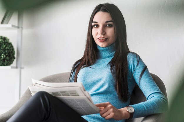 Frau mit der Zeitung, die Kamera betrachtet