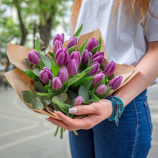 Frau mit einem Blumenstrauß von violetten Tulpen.