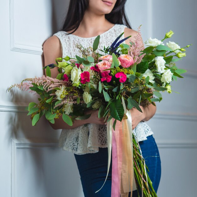 Frau mit einem großen Mischblumenstrauß mit Tüllbändern.