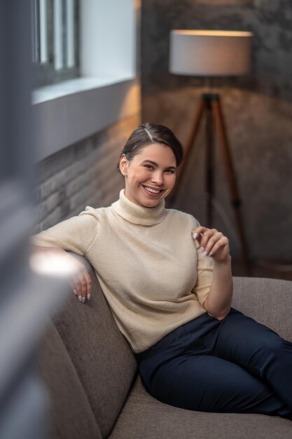 Frau mit einem strahlenden Lächeln, die in einem Raum sitzt