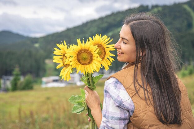 Frau mit einem Strauß Sonnenblumen in der Natur in einer bergigen Gegend