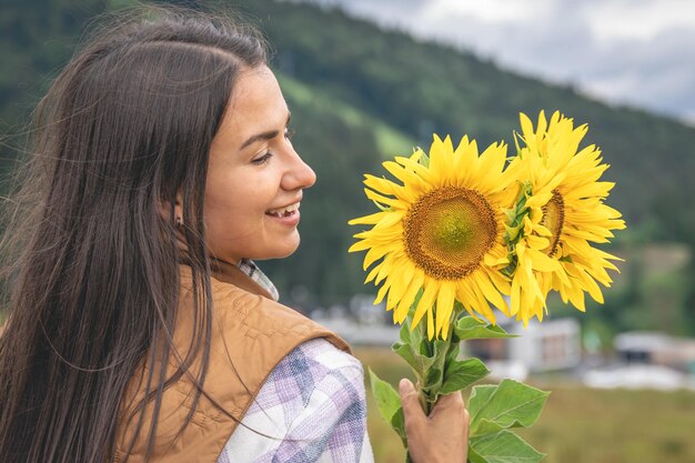 Frau mit einem Strauß Sonnenblumen in der Natur in einer bergigen Gegend
