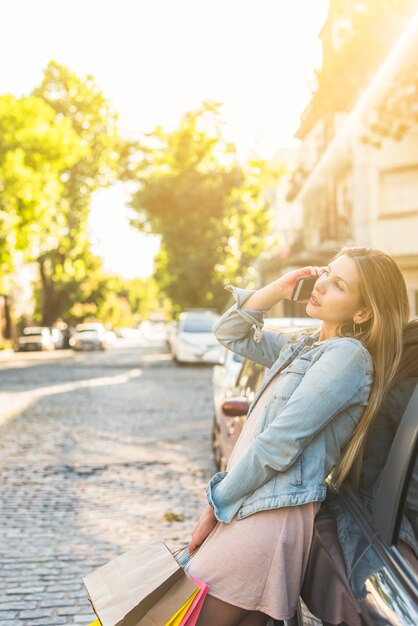 Frau mit Einkaufstüten in der Straße telefonisch sprechen