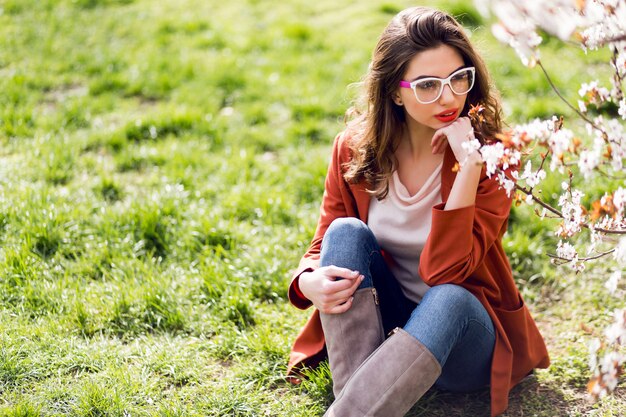 Frau mit erstaunlichen roten Lippen, kühle Brille auf dem Gras tragend