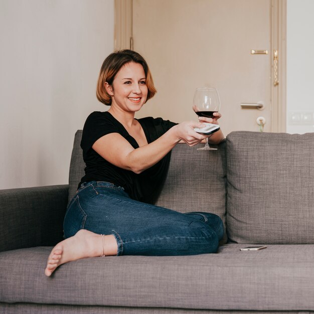 Frau mit Fernbedienung und Wein