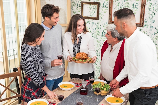 Kostenloses Foto frau mit gebackenem huhn am festlichen tisch