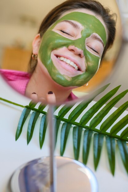 Frau mit Gesichtsmaske beim Betrachten im Spiegel