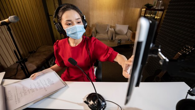 Frau mit Gesichtsmaske, die am Radio arbeitet