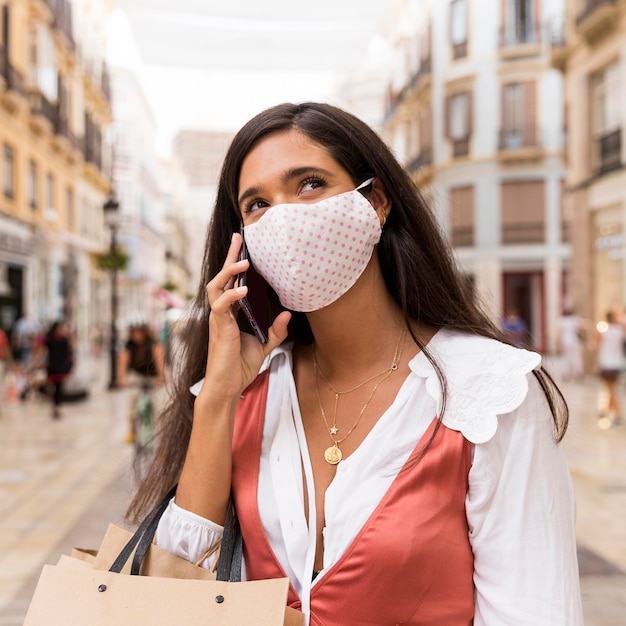 Kostenloses Foto frau mit gesichtsmaske, die am telefon spricht