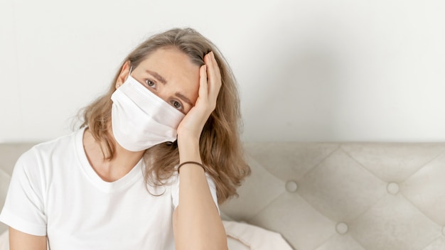 Frau mit Gesichtsmaske zum Schutz vor Kopfschmerzen und Husten wegen Coronavirus covid-19 im Quarantäneraum