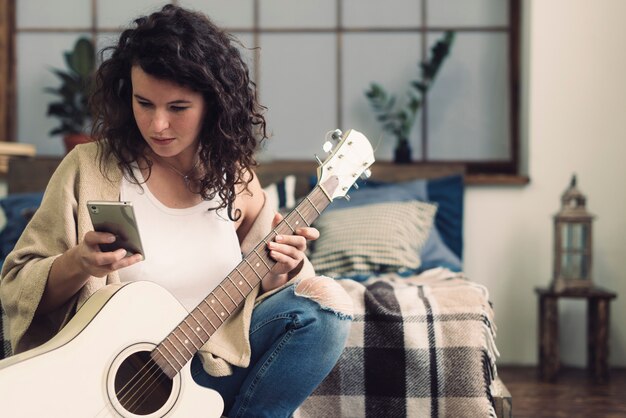 Frau mit Gitarre und Smartphone