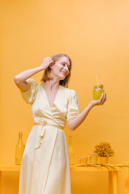 Frau mit Glas Limonade in einer gelben Szene