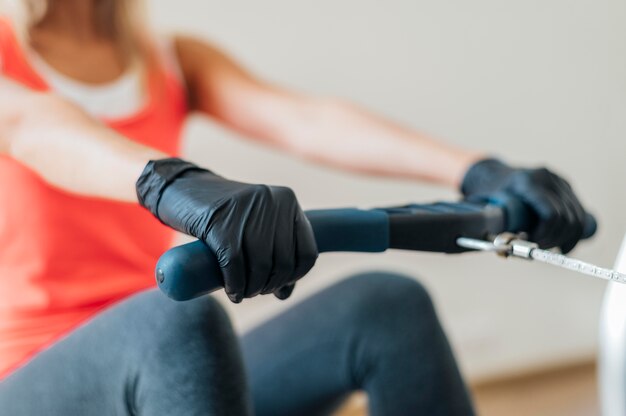 Frau mit Handschuhen, die im Fitnessstudio trainieren