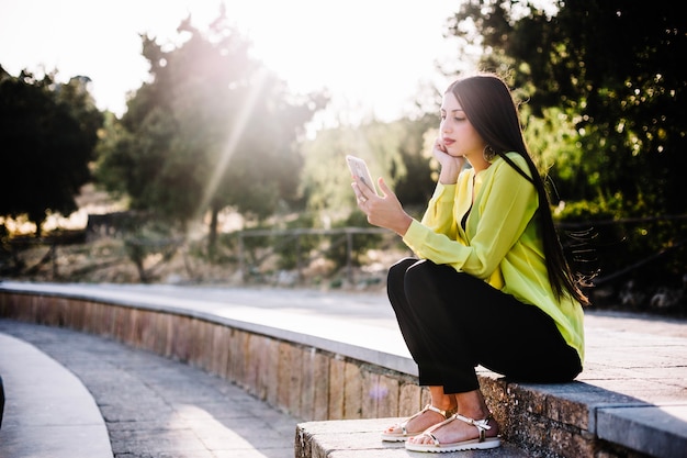 Frau mit Handy im sonnigen Park