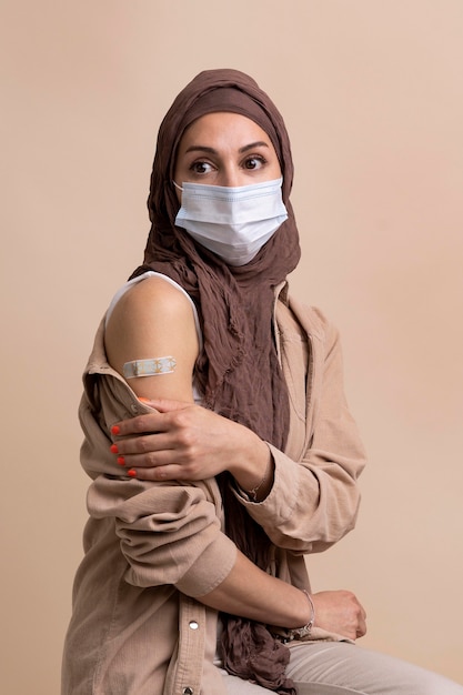 Frau mit Hijab, die nach einer Impfung einen Aufkleber am Arm zeigt